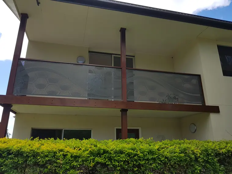 An upstairs balcony in Queensland with a one-off wave and hexagon pattern cut into Monument perforated balustrade panels between timber posts