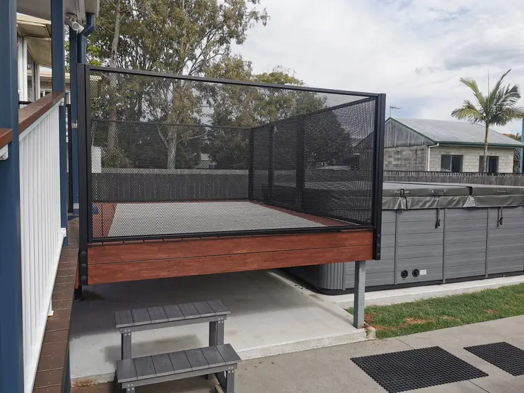 A raised timber deck in Queensland next to a swim spa, with black PurePerf panels along its open sides