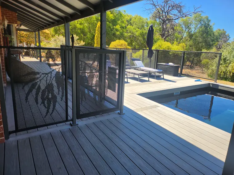A raised composite deck in Western Australia with a pool set into it, a perforated gate from the verandah and a perforated fence along the deck edge