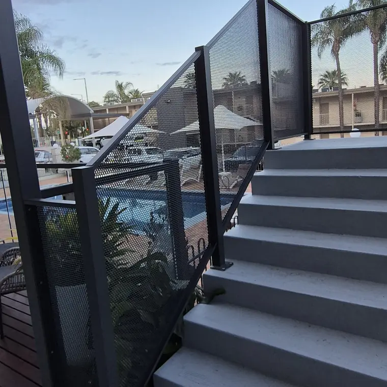 Concrete stairs in Victoria with a Monument perforated balustrade up the side, and a pool with umbrellas below