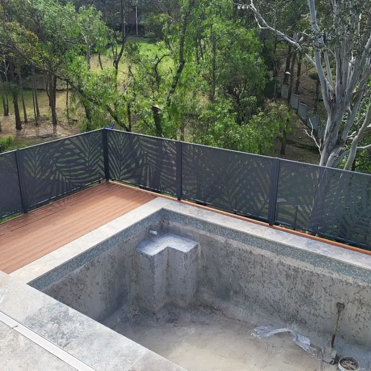 A raised pool terrace in New South Wales above bushland, with a Palmy Perf fence along the edge and the pool still being built