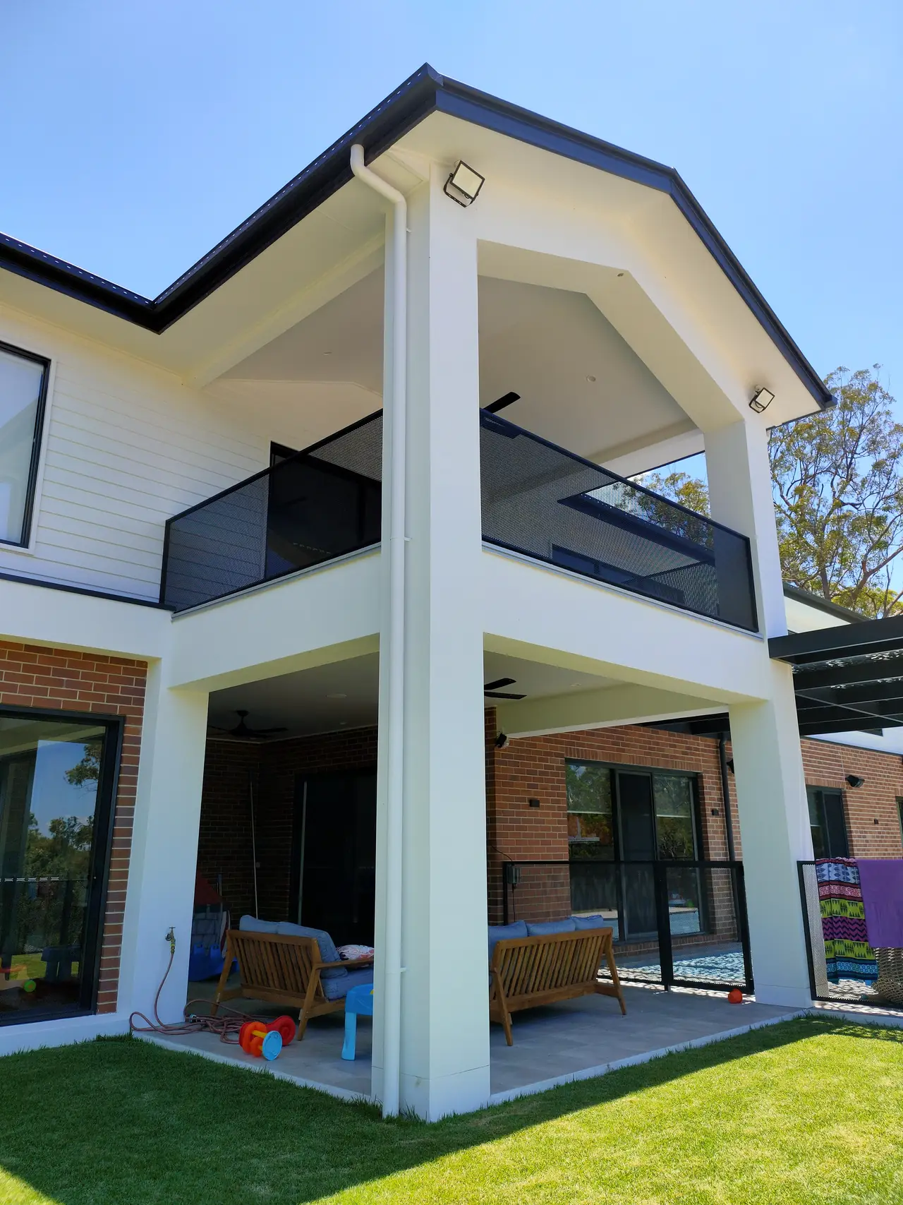 A two-storey home in Queensland with a black PurePerf balustrade around the upstairs balcony and an outdoor living area below