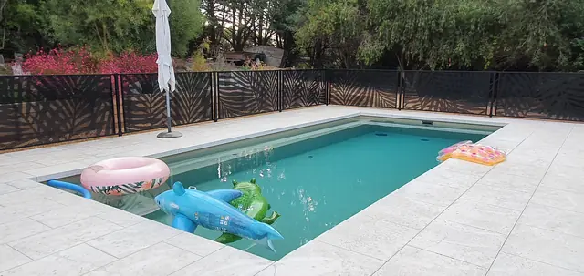 A black Palmy Perf design pool fence around a pool with pool toys
