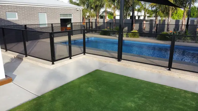 A black PurePerf fence between artificial turf and a long pool
