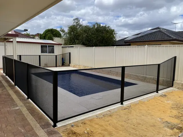 A black PurePerf fence around a plunge pool and a paved courtyard