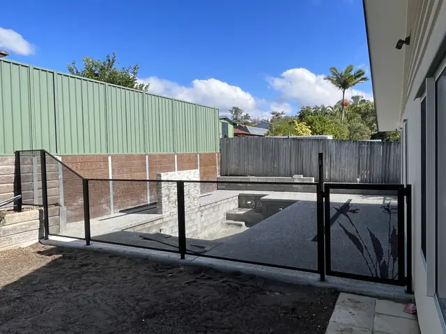 A black PurePerf fence and gate around a new pool beside the house
