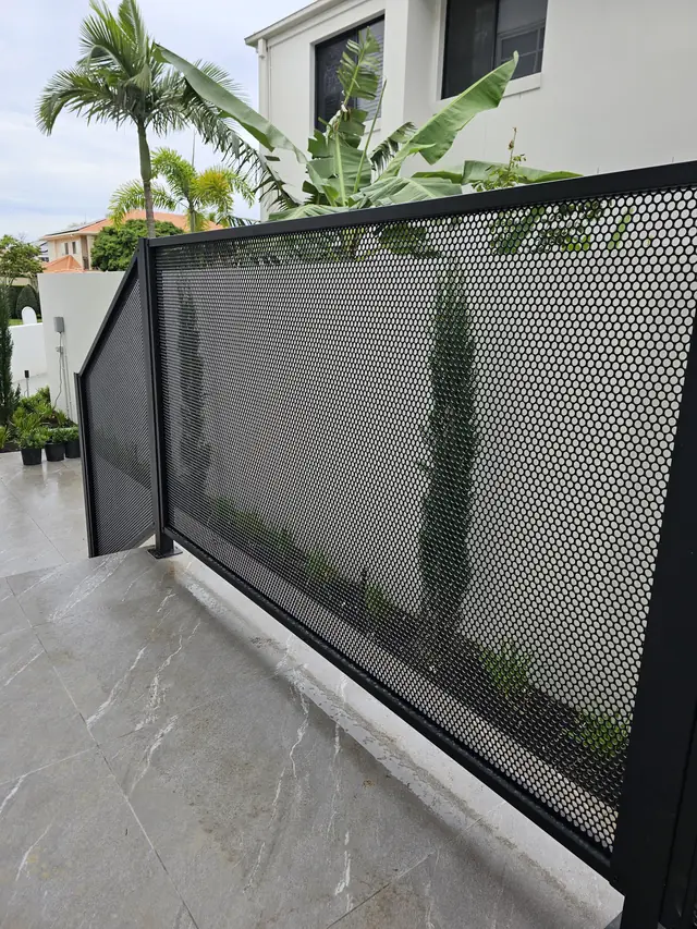 A black PurePerf panel along a tiled path, with tall plants seen through it