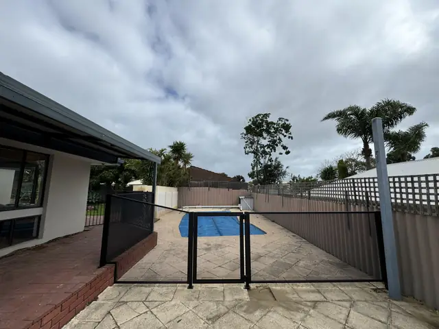 A black PurePerf pool gate in a fence beside a covered pool