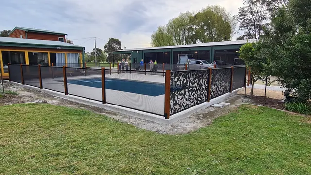 A black Ficus Perf design pool fence and plain panels around a pool