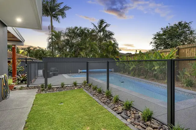 A Monument PurePerf fence along a lap pool and a garden at dusk