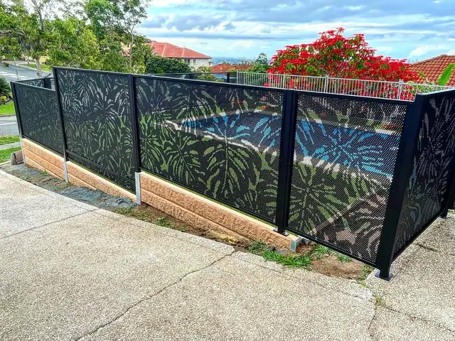 A black Monstera Perf design pool fence on a sloping block