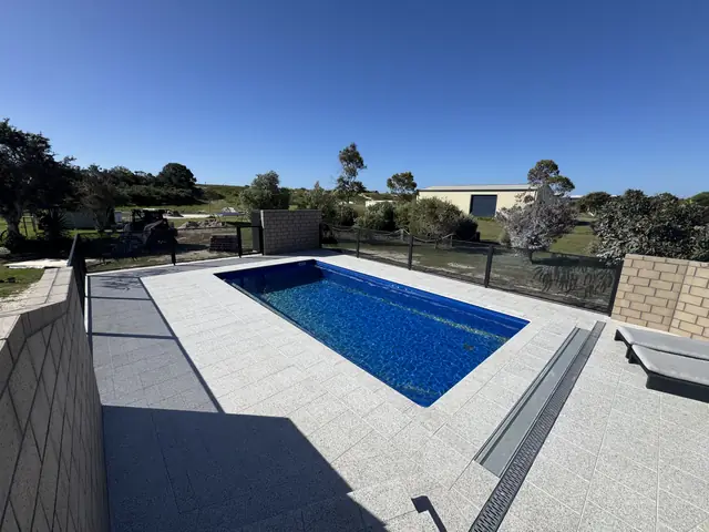 A black PurePerf fence along a raised pool surround under a blue sky