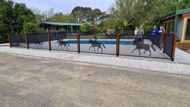 A black one-off custom fence with horses and riders cut into it