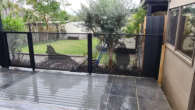 A black one-off custom fence with a dog silhouette, on a wet deck