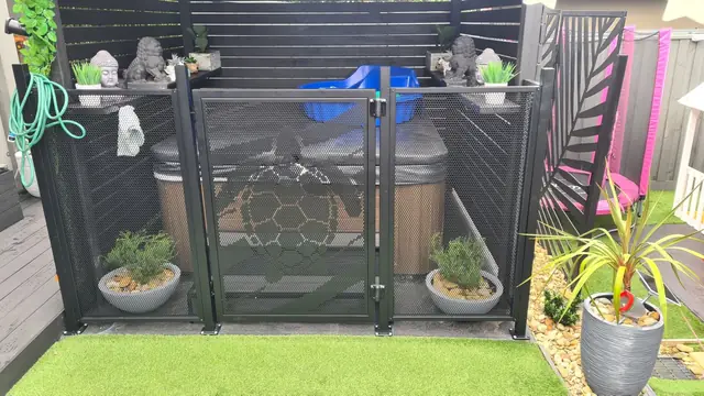 A black one-off custom gate with a turtle cut into it, in front of a spa