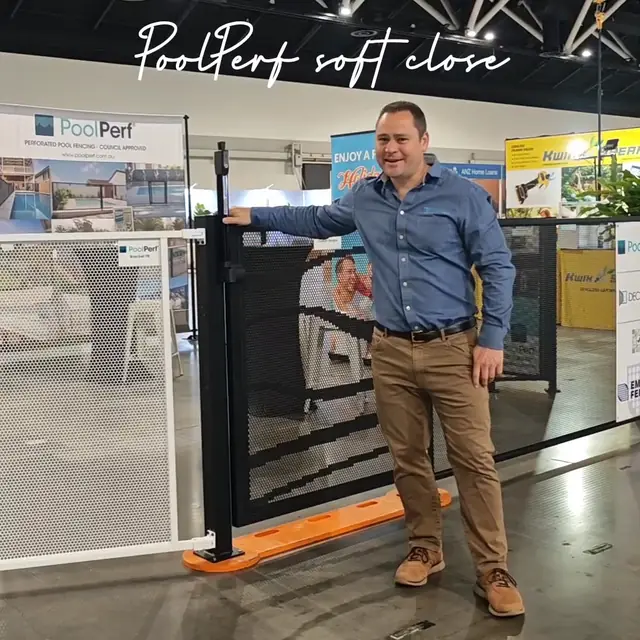 Jason Brown with his hand on a black PoolPerf gate at the PoolPerf home show stand, with the words PoolPerf soft close