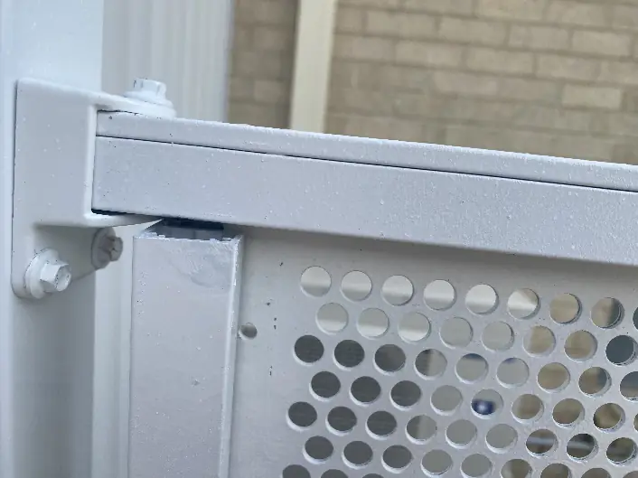 Close up of a top corner of an imported perforated fence panel, where the top rail and the side of the frame do not meet