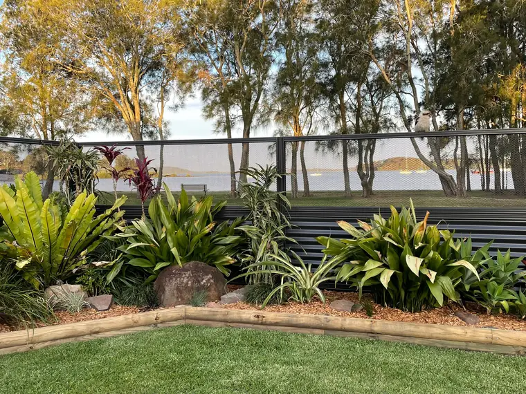 Textured Monument PoolPerf panels fixed on top of a dark slatted fence, looking through to a lake and trees