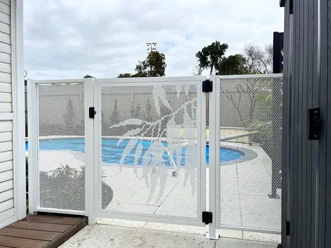 A white Gum design pool gate, the pool showing through the leaves