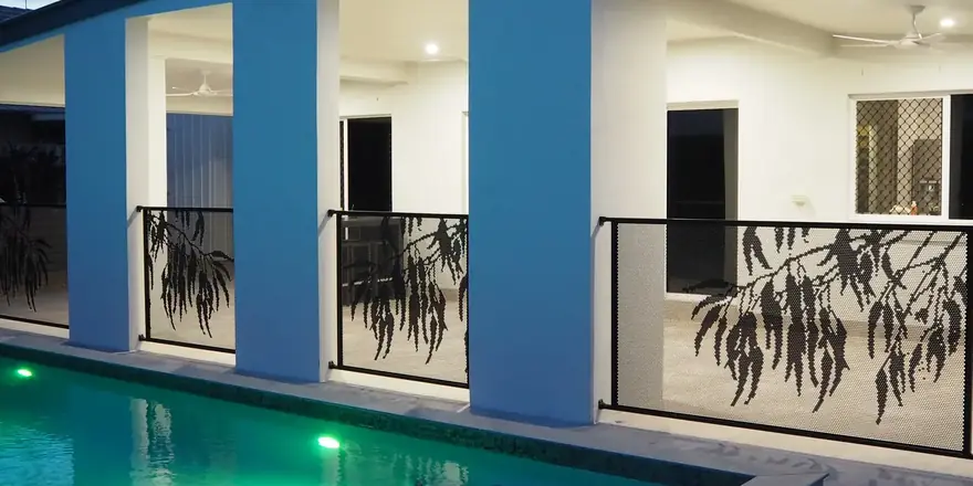 Black Gum design PoolPerf panels between the columns of a two storey home, beside a lit pool