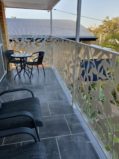 White Ficus design balustrade panels along a tiled balcony with a small outdoor table