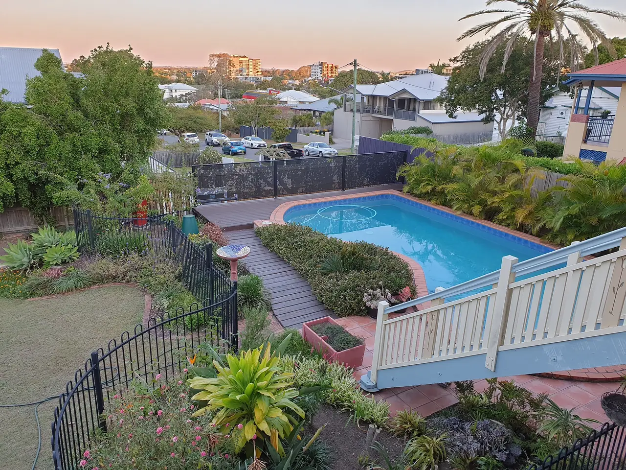 Looking down a terraced Queensland garden to a pool, with black Fig Leaves design panels along the top boundary
