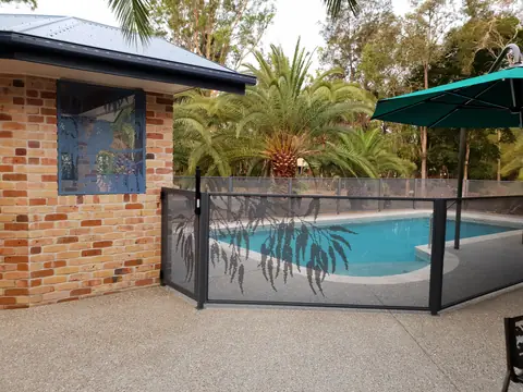 Textured Ironstone Gum design panels and gate beside a pool, with a brick wall and a palm behind