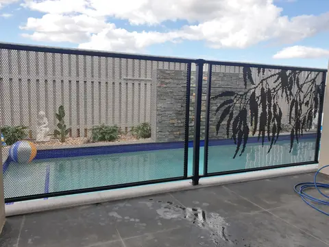 A black Gum design gate and panels in a pool fence, the gum leaves hanging from the top of each panel