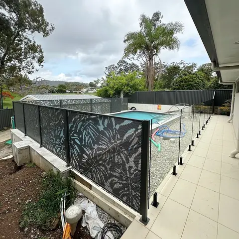 Black Monstera design panels along a pool garden, with glass along the walkway by the house