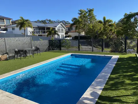 Monstera design panels across a backyard pool area, seen from beside the house