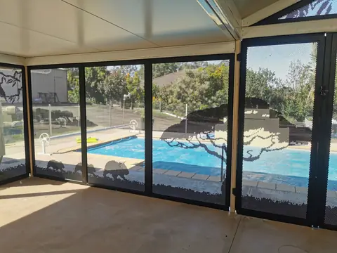 Monument grey panels with a gum tree and kangaroos cut into them, seen through a covered outdoor room