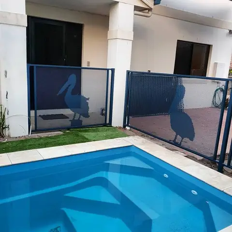Deep Ocean blue gate and panels with pelicans cut into them, beside a small pool