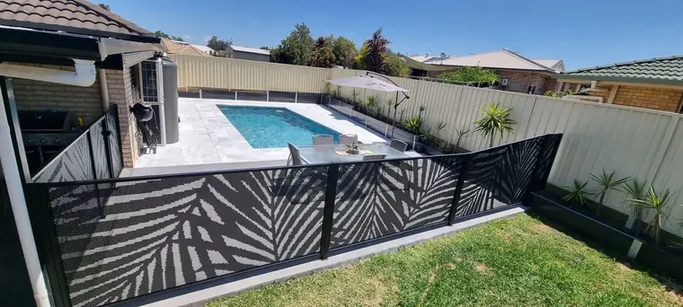 Black Palmy design panels around a pool and lawn, seen from beside the house