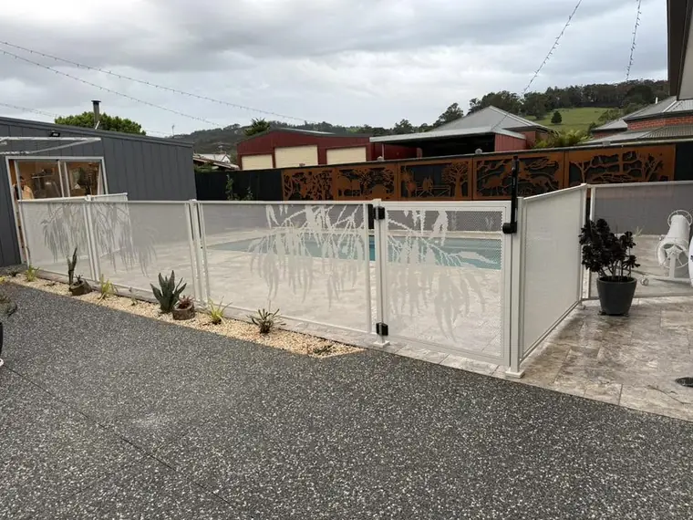 A Surfmist pool fence with Gum design panels and gate beside a driveway