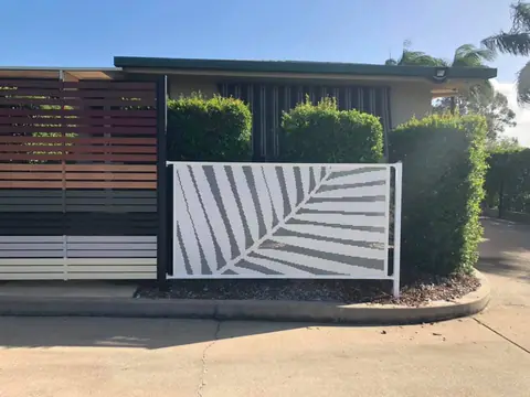 A white panel with one large palm frond cut into it, set in front of a hedge in Queensland