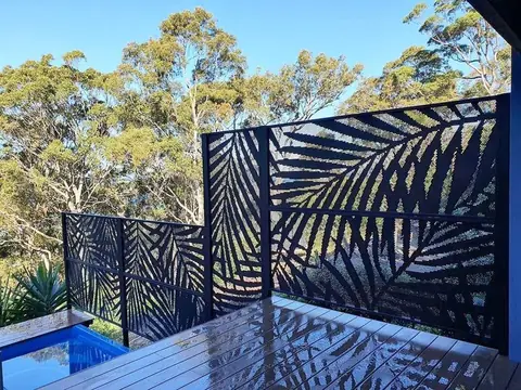 Tall black Palmy design screens on a timber deck above a pool, looking out to gum trees