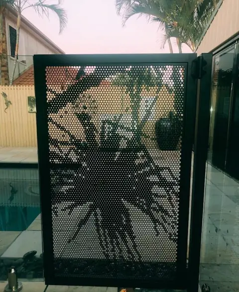 A black Pandanus design pool gate, the frond silhouette filling the panel