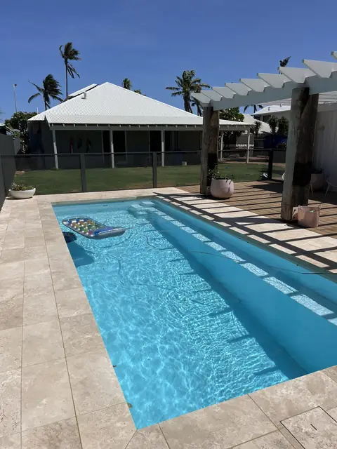 A Woodland Grey PurePerf fence along a narrow pool in Western Australia, with a pergola beyond