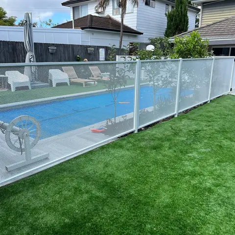 A white PurePerf fence and gate around a pool, with tropical planting along the house