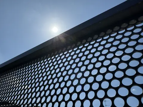 Looking up at a Textured Ironstone PurePerf panel against the sun, showing the even round perforations