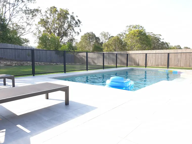 The two sides of the pool that have a black PoolPerf fence, with the trees behind clearly visible through it