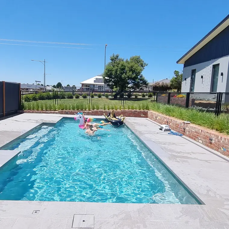 A lap pool with a pool toy floating in it, and a black PoolPerf fence along the far side, in Victoria