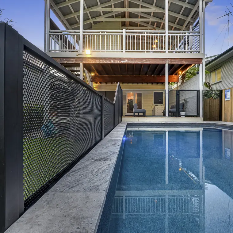 A black PoolPerf panel photographed up close beside a lap pool, with the holes visible and the pool behind