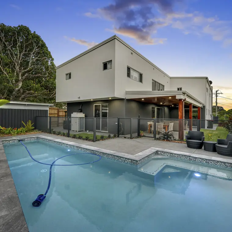 A grey Monument PoolPerf fence around a backyard pool at dusk, still see-through