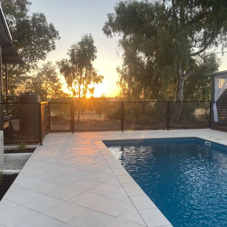 The sun setting behind a black PoolPerf fence in Western Australia, seen through the panel from the pool deck