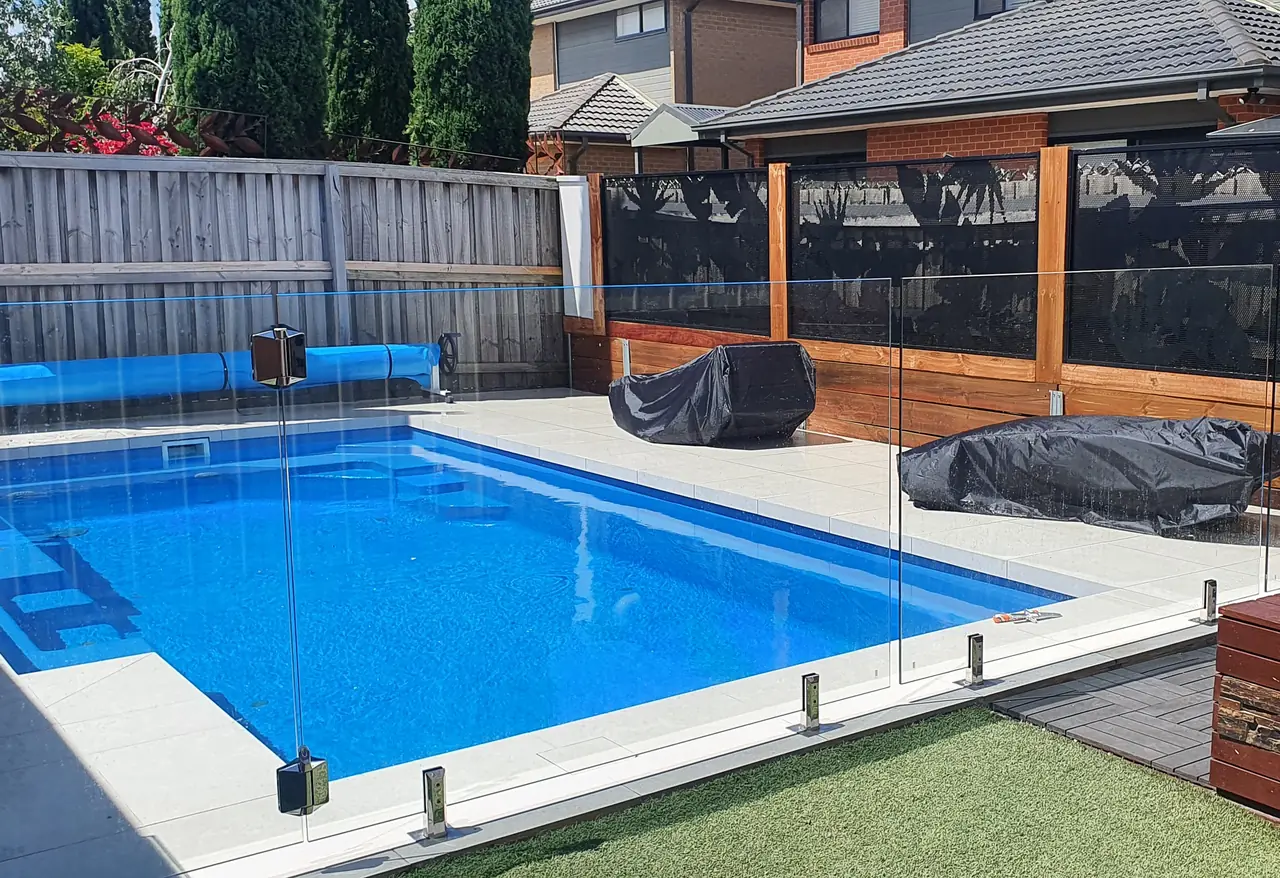 Glass across the front of a Victorian pool, and custom banana leaf PoolPerf panels set into a timber framed screen wall at the back