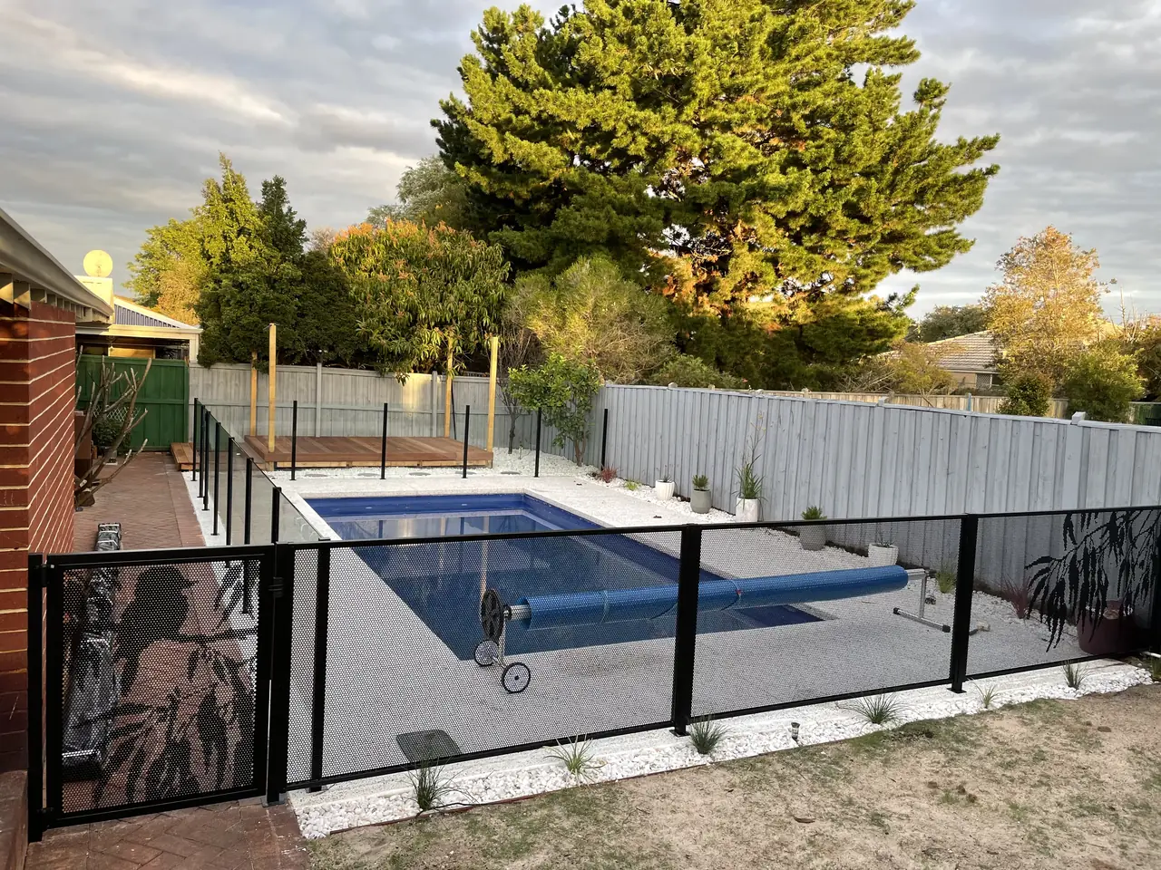 A pool in Western Australia with a black PoolPerf gate carrying a custom silhouette design, plain PurePerf beside it, and glass along the far side