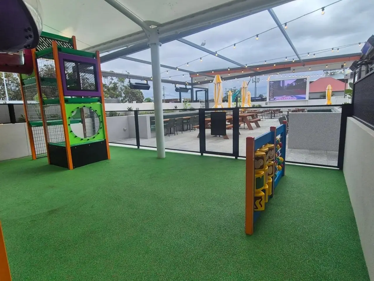 The play area at the Swansea Hotel, with black perforated panels between the play equipment and the beer garden tables