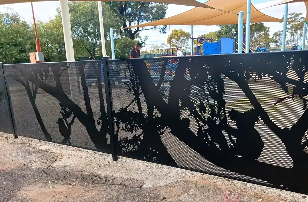 A black perforated fence with a gum tree silhouette around a school playground in Queensland