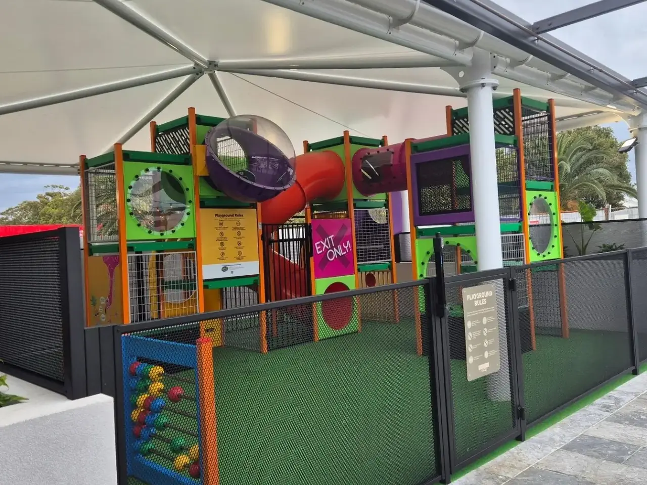 A children’s play centre under a shade roof at the Swansea Hotel, fenced with black perforated panels